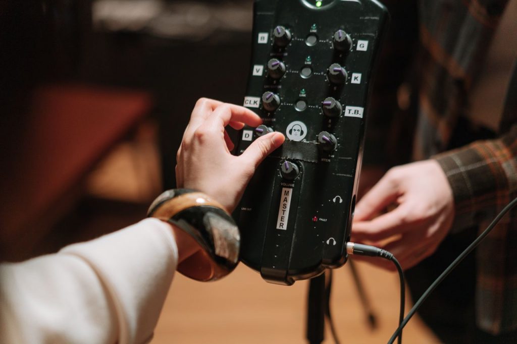 Close-up of hands adjusting audio device controls for music production and recording.